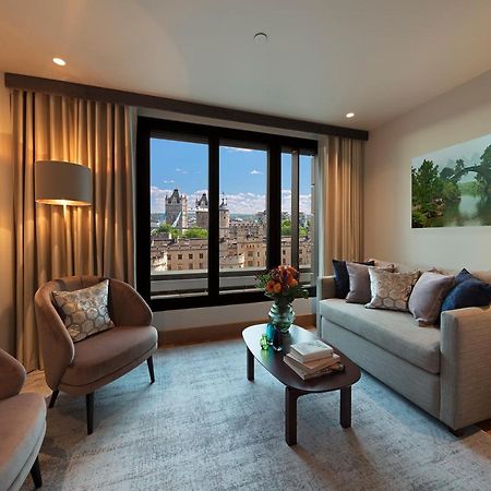 Tower Suites By Blue Orchid لندن المظهر الخارجي الصورة The photo depicts a modern living room with a contemporary design. It features two stylish, circular chairs and a comfortable sofa adorned with various decorative pillows. A small coffee table is positioned in front of the sofa, topped with books and