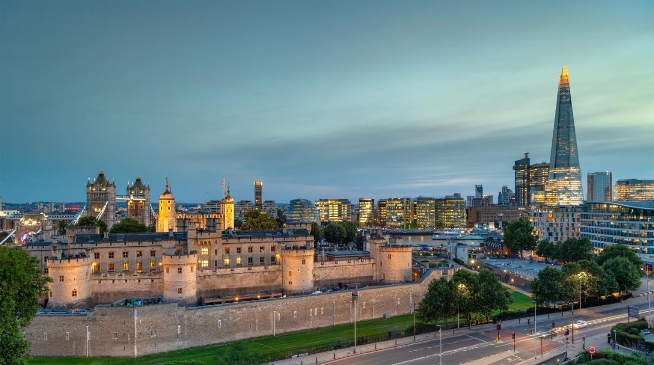 Tower Suites By Blue Orchid لندن المظهر الخارجي الصورة The photo shows a view of a historical site and modern skyline. In the foreground, there is a prominent historical building, likely a castle or fortress, featuring tall towers and a stone wall. This structure is set against a backdrop of contemporary