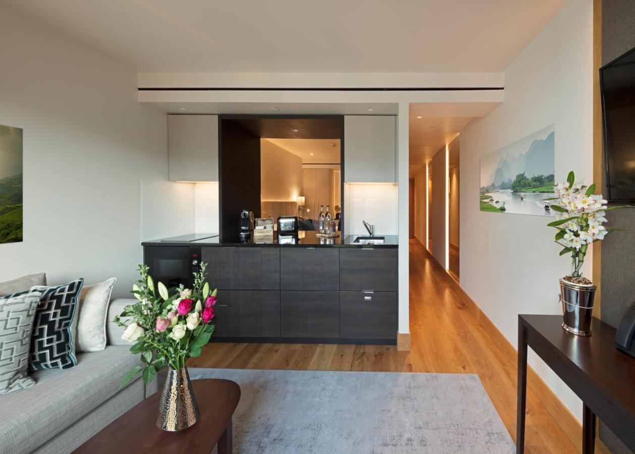 Tower Suites By Blue Orchid لندن المظهر الخارجي الصورة The photo showcases a modern and stylish interior space, likely a living area of a luxurious apartment or hotel suite. 

- **Bar Area**: There is a sleek bar counter that features a variety of bottles and glassware, suggesting a well-equipped space f