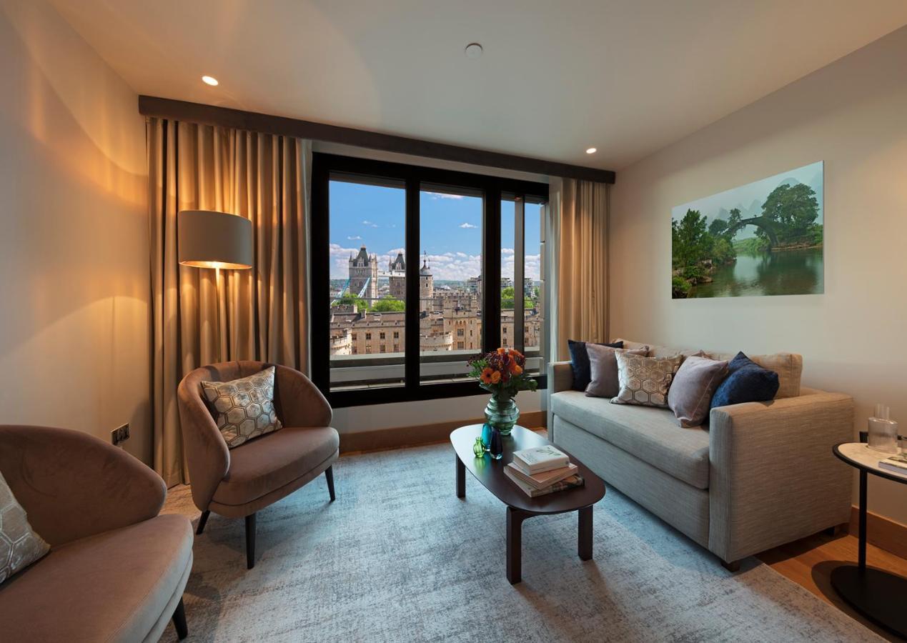 Tower Suites By Blue Orchid لندن المظهر الخارجي الصورة The photo depicts a modern living room with a contemporary design. It features two stylish, circular chairs and a comfortable sofa adorned with various decorative pillows. A small coffee table is positioned in front of the sofa, topped with books and