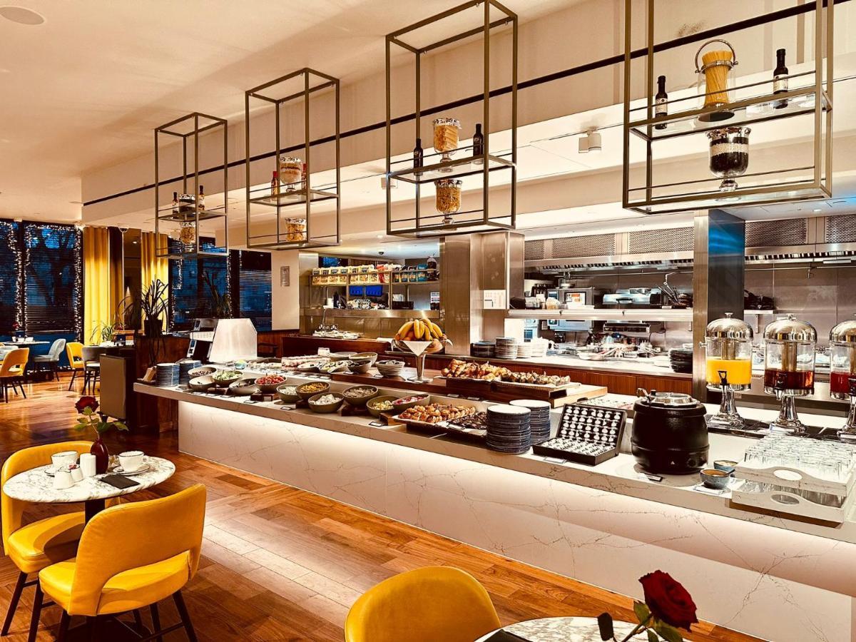 Tower Suites By Blue Orchid لندن المظهر الخارجي الصورة The photo shows a modern restaurant interior featuring a buffet layout. The space has a sleek design with wooden flooring and a bright, open atmosphere.  

The buffet counter is richly arranged with various dishes and food items, likely for a breakfa
