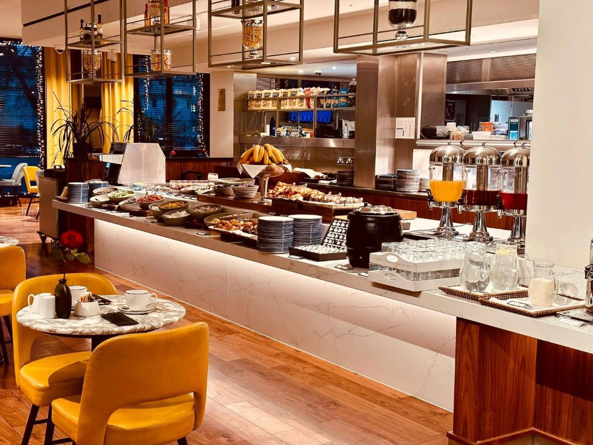 Tower Suites By Blue Orchid لندن المظهر الخارجي الصورة The photo depicts a modern buffet setting, featuring an array of food items displayed elegantly on a long countertop. There are various dishes, likely including pastries, fruits, and other breakfast items, arranged neatly. In the background, there ar