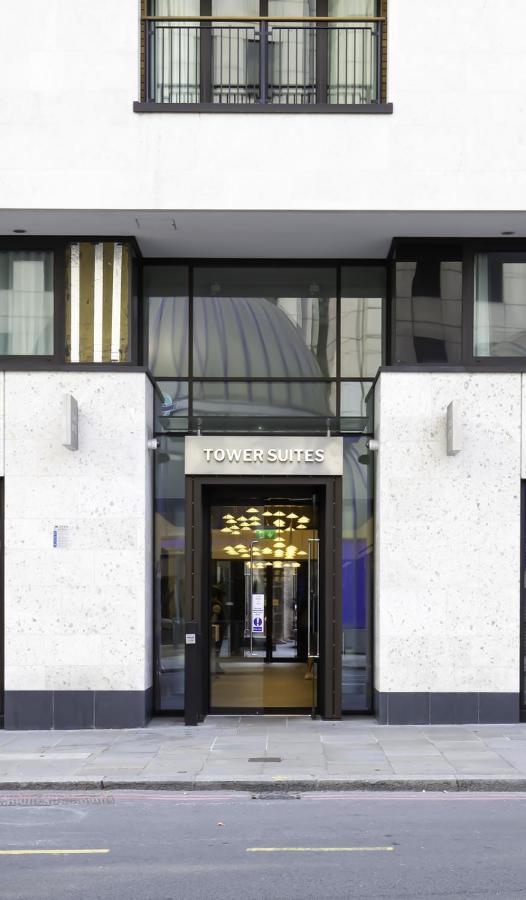 Tower Suites By Blue Orchid لندن المظهر الخارجي الصورة The photo shows the entrance of a building labeled "TOWER SUITES." The entrance features large glass doors, allowing visibility into the interior. The building has a modern architectural style, with a light-colored stone facade and some decorative el