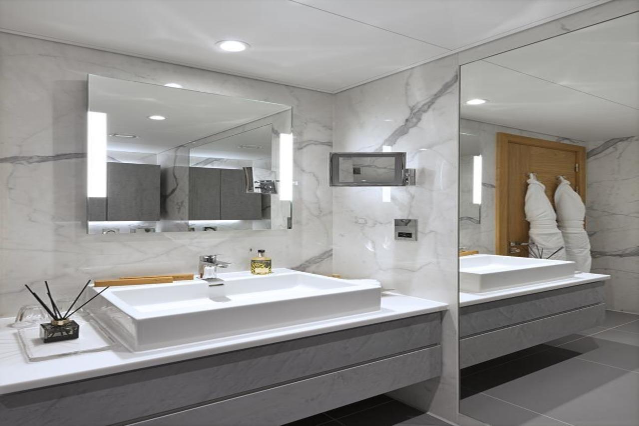 Tower Suites By Blue Orchid لندن المظهر الخارجي الصورة The photo shows a modern bathroom featuring a sleek design. 

- **Vanity Area**: There is a rectangular sink set into a white countertop, paired with a minimalist faucet. 
- **Mirrors**: Above the sink, there is a large mirror that reflects the entir